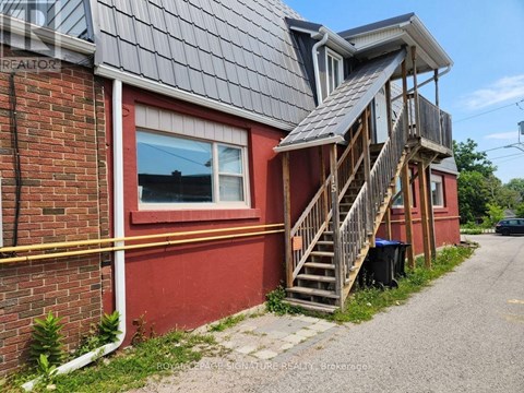 A red house with a grey roof and a wooden staircase leading to the second floor.