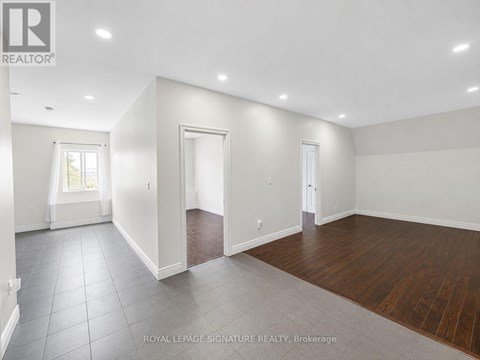 A spacious room with white walls and wooden flooring.