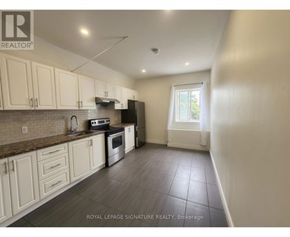 A kitchen with white cabinets and a tiled floor.