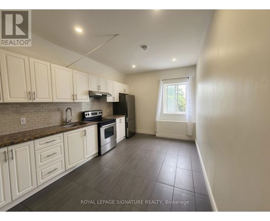 A kitchen with white cabinets and a tiled floor.