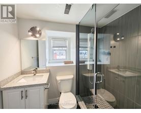 A bathroom with a toilet, sink, and shower.