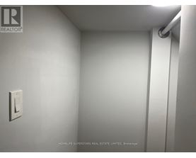 A white wall with a light switch and a pipe.