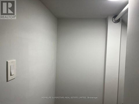 A white wall with a light switch and a pipe.