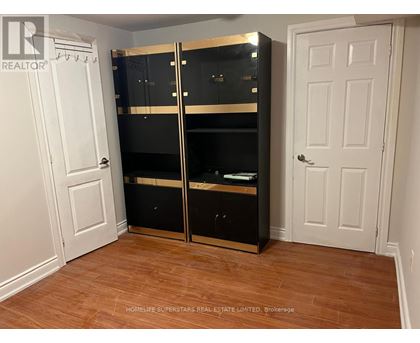A large black wardrobe with a mirrored door is in a room with a white door and wooden flooring.