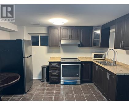 A kitchen with a refrigerator, microwave, and sink.