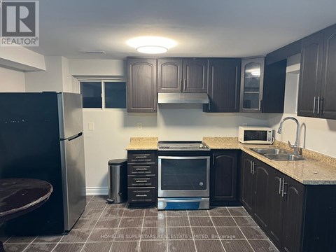 A kitchen with a refrigerator, microwave, and sink.