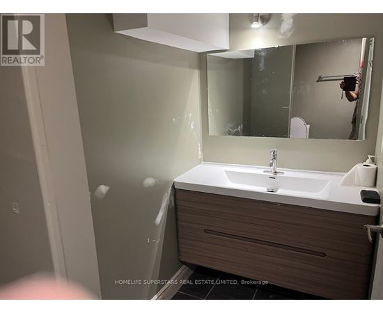 A bathroom with a sink, mirror, and toilet paper holder.