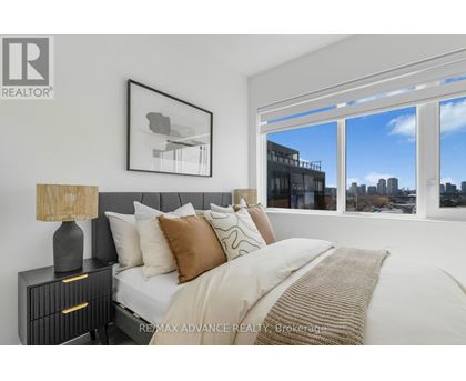 A bedroom with a large bed, a nightstand with a lamp, and a framed picture on the wall.