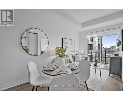 A dining room with a white table and chairs, a round mirror, and a view of the city.