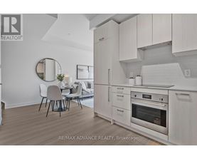 A modern kitchen with white cabinets and a dining table.
