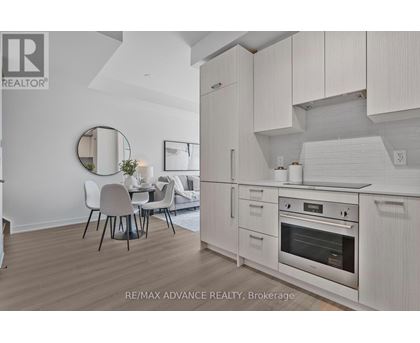 A modern kitchen with white cabinets and a dining table.