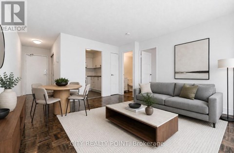 A modern living room with a grey sofa, a wooden coffee table, and a dining table with chairs.