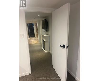 A hallway with a TV on the wall and a door on the right.