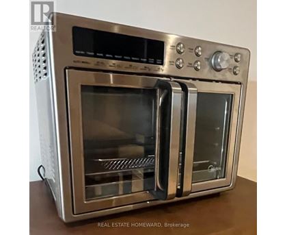 A silver oven with a digital display and control panel on top.