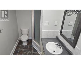 A bathroom with a toilet, sink and mirror.