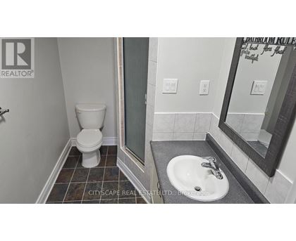 A bathroom with a toilet, sink and mirror.