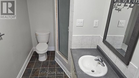 A bathroom with a toilet, sink and mirror.