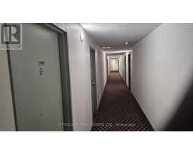 A long hallway with doors on either side and a sign on the wall.