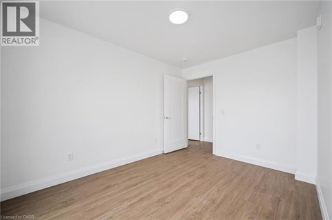 A spacious room with wooden flooring and white walls.