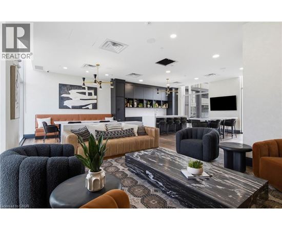 A modern living room with a black and white rug, a black coffee table, and a large painting on the wall.