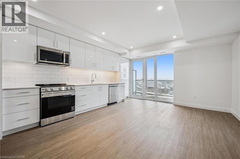 A well-lit, spacious kitchen with white cabinets and a stainless steel oven.