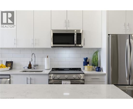 A modern kitchen with white cabinets and stainless steel appliances.