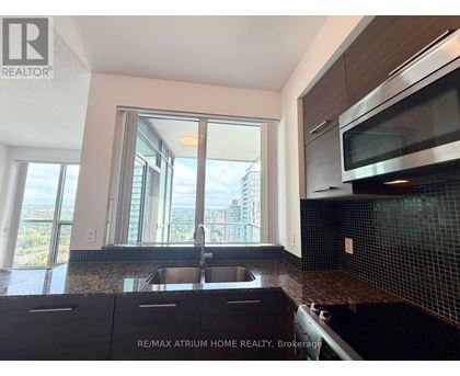 A kitchen with a sink and a window overlooking a cityscape.