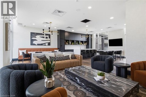 A modern living room with a black and white rug, a black coffee table, and a large painting on the wall.