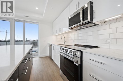 A modern kitchen with white cabinets and a black stove top oven.