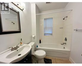 A white toilet sits next to a white bathtub in a bathroom.
