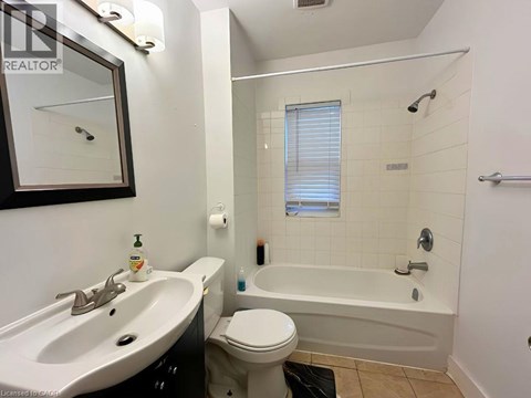 A white toilet sits next to a white bathtub in a bathroom.