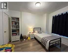 A bedroom with a bed, nightstand, and bookshelf.