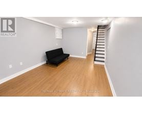 A black sofa sits in a room with wooden floors and white walls.