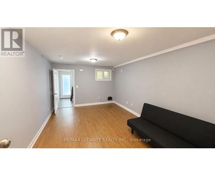 A living room with a black couch and a doorway leading to another room.