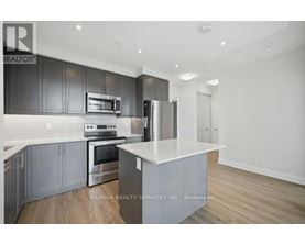 A modern kitchen with dark grey cabinets and stainless steel appliances.