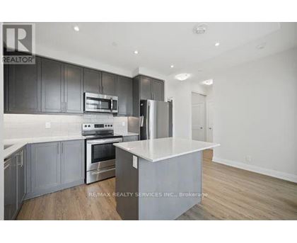 A modern kitchen with dark grey cabinets and stainless steel appliances.