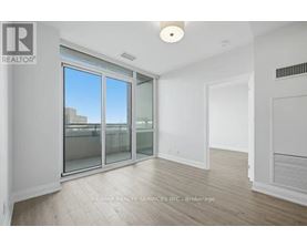 A spacious room with a sliding glass door leading to a balcony.