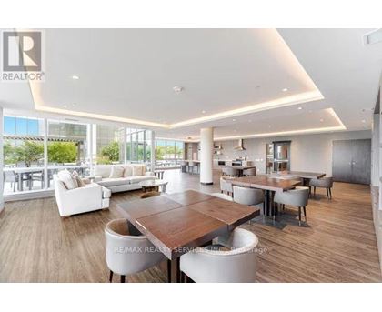 A spacious living room with a large wooden table and white chairs.