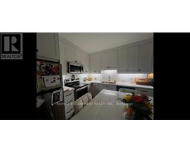 A kitchen with white cabinets and a fridge.