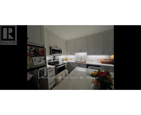 A kitchen with white cabinets and a fridge.