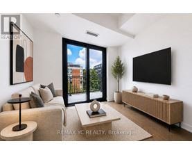 A living room with a couch, a table, a television, and a plant.