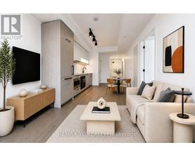 A modern living room with a large couch, a coffee table, and a flat-screen TV mounted on the wall.