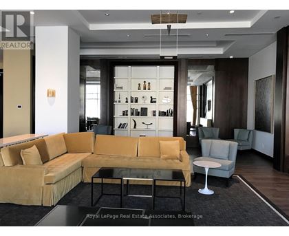 A living room with a yellow couch and a glass coffee table.