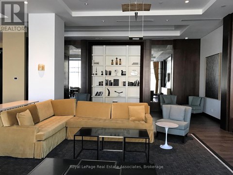 A living room with a yellow couch and a glass coffee table.