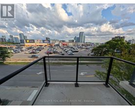 A view from a balcony overlooking a parking lot with a city skyline in the distance.