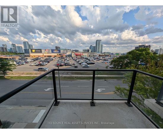 A view from a balcony overlooking a parking lot with a city skyline in the distance.