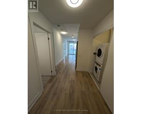 A long hallway with a washer and dryer in the corner.