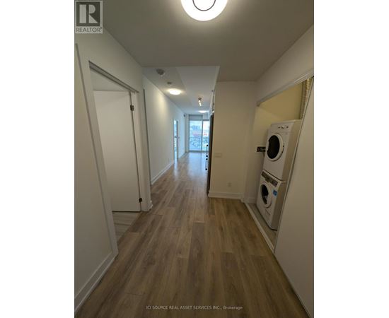 A long hallway with a washer and dryer in the corner.