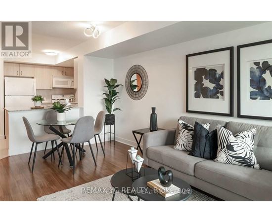 A living room with a grey couch and a dining table with chairs.