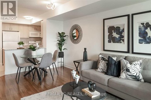 A living room with a grey couch and a dining table with chairs.